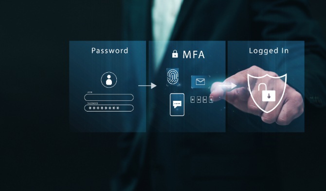 A man using his computer and phone for multi-factor authentication to access his emails.