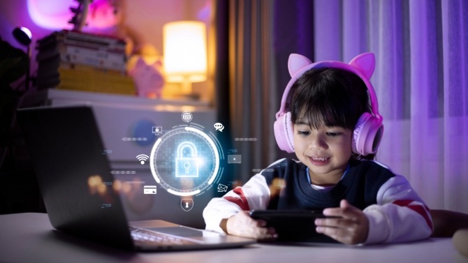 Young child in front of a device, wearing pink headphones with cat ears