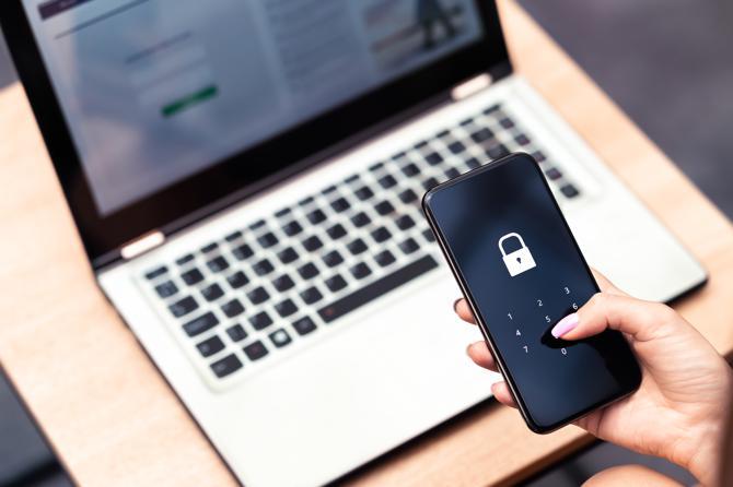 A woman secures her phone and computer from online banking fraud.