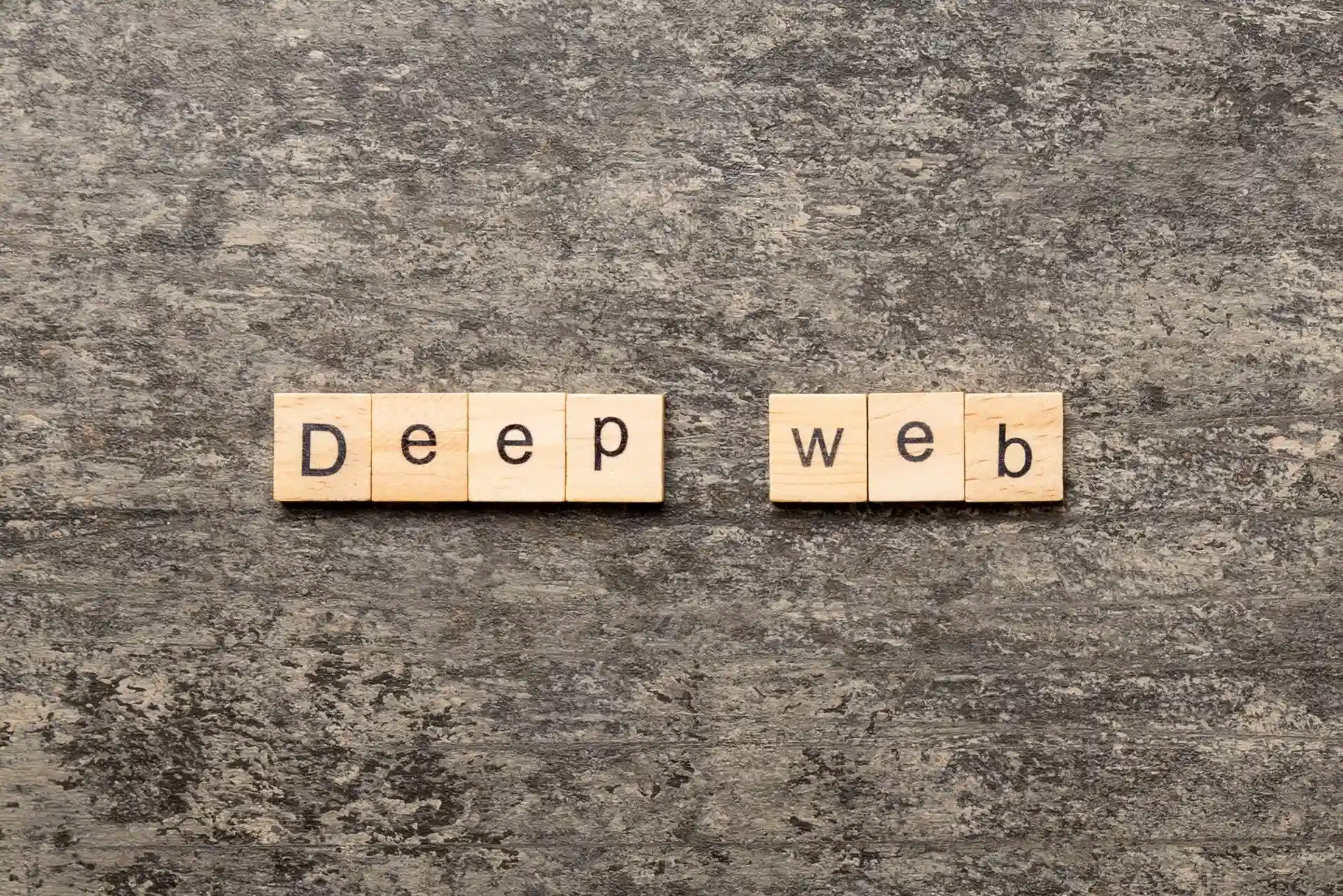 Wooden letter tiles spelling “Deep Web” on a textured gray background.