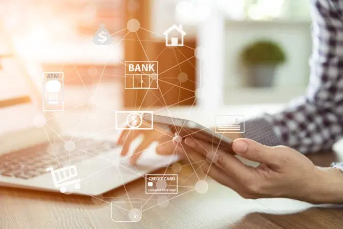 Une femme utilisant les conseils de sécurité d’une banque en ligne sur un ordinateur portable et un téléphone.