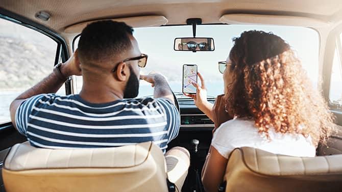 pareja viajando en coche mientras buscan redes wi-fi en su teléfono móvil