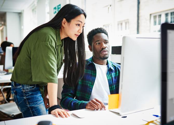 Due colleghi in ufficio che osservano lo schermo di un computer