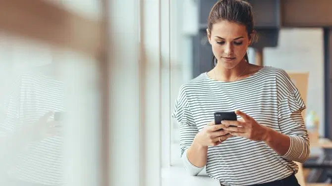 امرأة تنظر إلى هاتفها المحمول