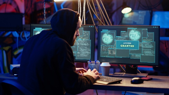A hacker attempts to crack a password with a computer and smartphone.