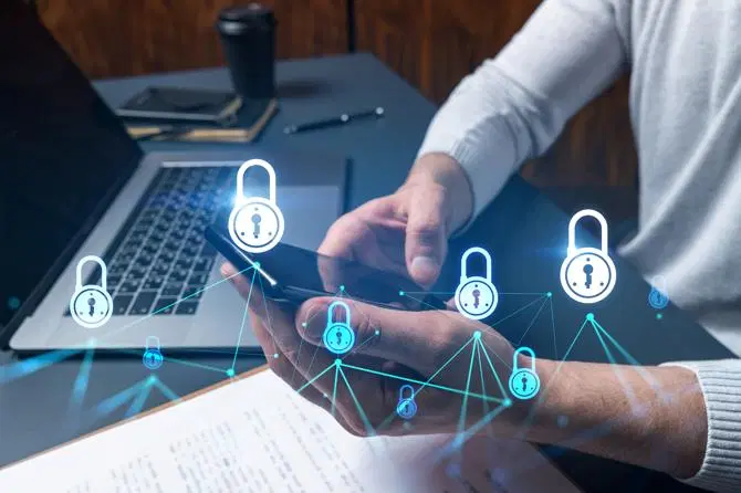 Ein Mann benutzt seinen Laptop und sein Handy, die mit Kryptographie geschützt sind.