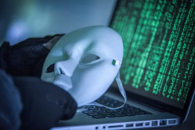 An hacker mask next to a computer