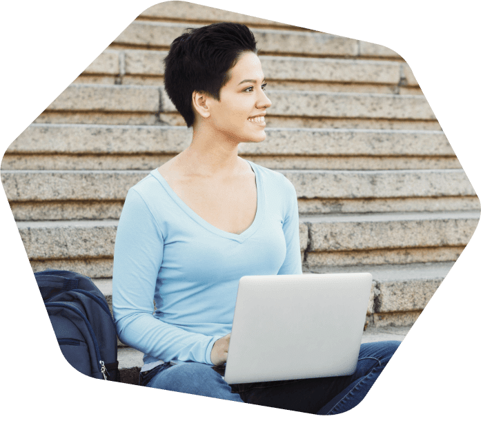 Dame assise sur les marches à l'extérieur en travaillant sur son ordinateur portable