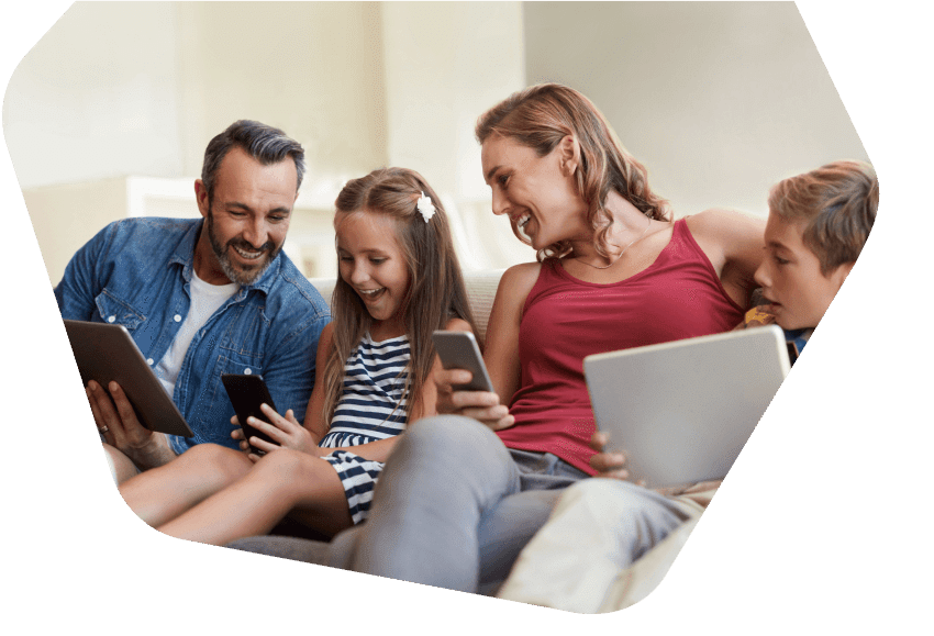 Famille heureuse assise ensemble tous en utilisant des appareils à la maison