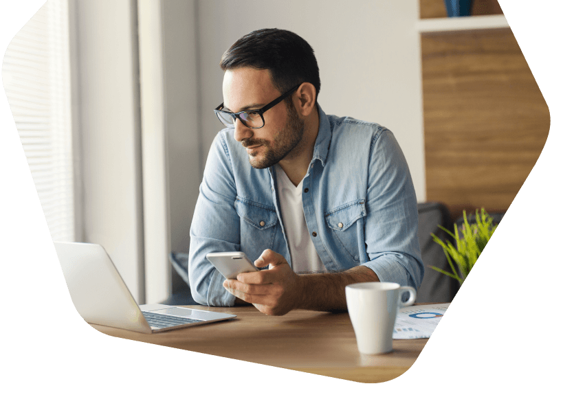 Man at home working using his phone and laptop