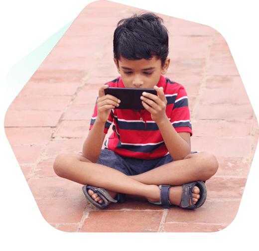 Ung pojke som sitter och tittar på videor på sin mobiltelefon
